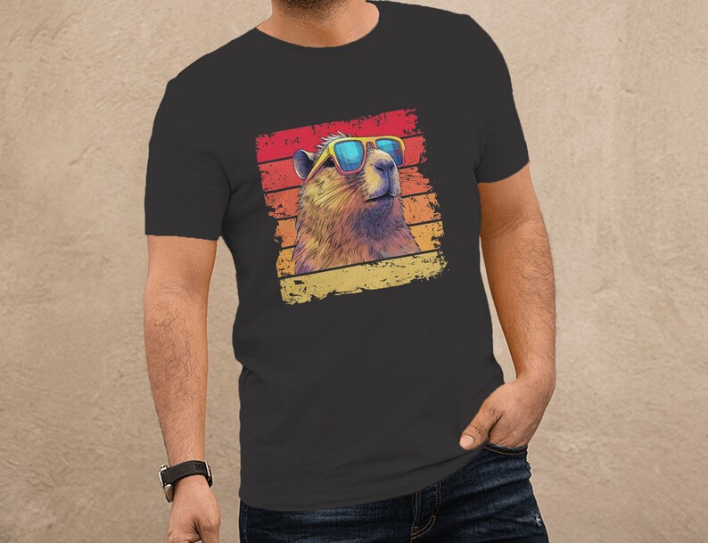 May include: A dark gray t-shirt with a retro-style graphic of a marmot wearing sunglasses. The graphic is set against a colorful striped background.