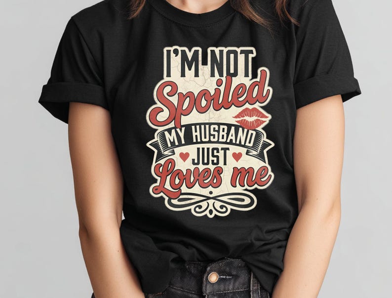 Puede incluir: Camiseta negra con el texto "I'M NOT Spoiled MY HUSBAND JUST Loves me" en letras rojas y blancas. El dise&ntilde;o incluye labios y corazones rojos, con un estilo vintage.