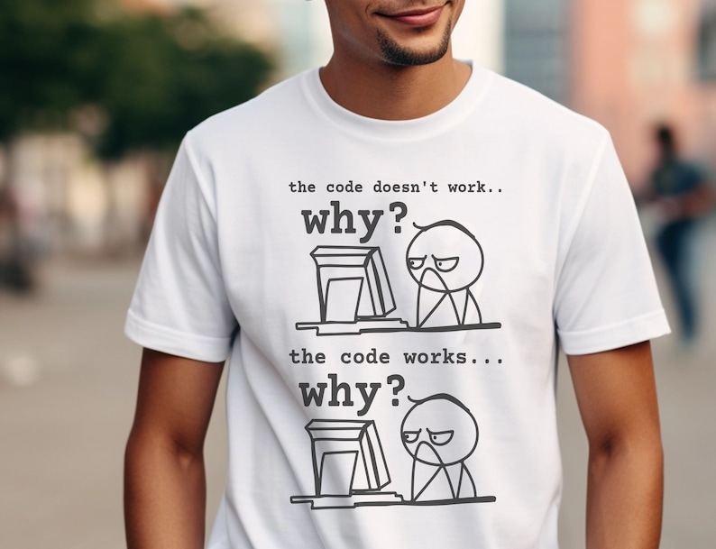 May include: White t-shirt featuring a humorous graphic about coding. The text reads "the code doesn't work... why?" and "the code works... why?" with stick figure illustrations of a person at a computer.