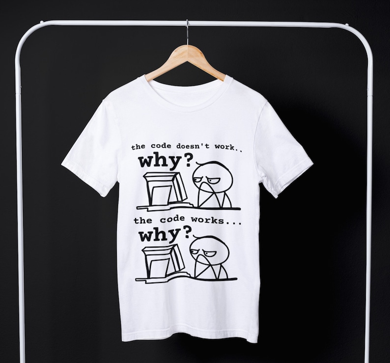 May include: White t-shirt with a black and white illustration of a person at a computer. The text on the shirt reads "the code doesn't work... why?" and "the code works... why?"