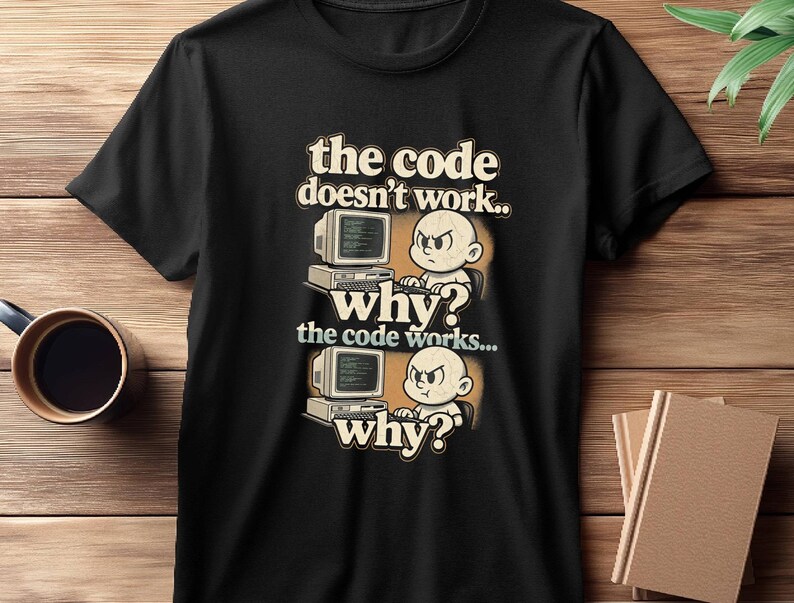 May include: Black t-shirt with a retro-style graphic. The design features a cartoon baby with an angry expression in front of a computer, with the text "the code doesn't work.. why? the code works... why?"