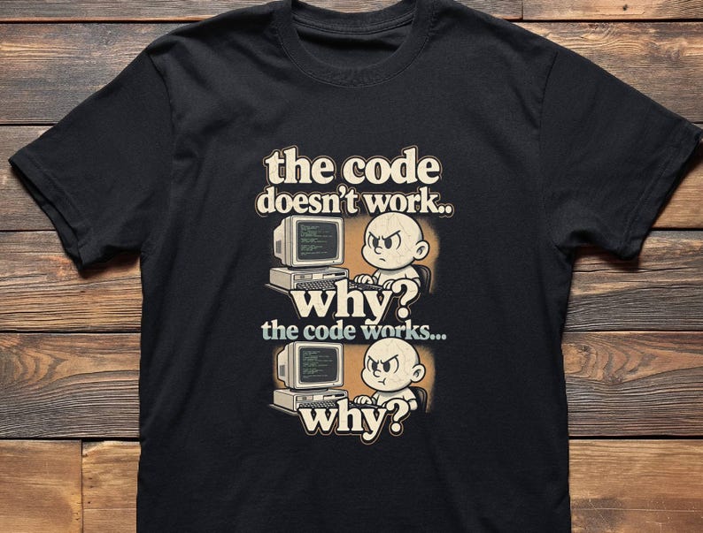 May include: Black t-shirt with a humorous graphic. The design features a cartoon baby with an angry expression in front of a computer, with the text "the code doesn't work.. why? the code works... why?"