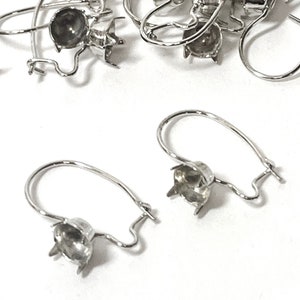 May include: Silver earring findings with a round bezel setting. The findings are designed to hold a cabochon stone.