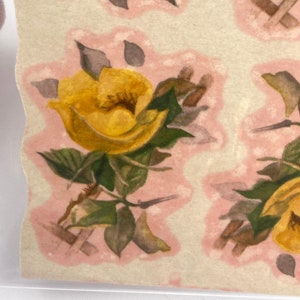 May include: A sheet of vintage yellow rose patterned paper with a pink background. The roses are surrounded by green leaves and thorns.