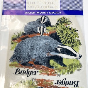 May include: Two water-mount decals of a badger, one adult and one baby, in a forest setting. The decals are labeled "Badger" and "Color Brite" with the text "95250 2 PCS MADE IN ENGLAND WATER-MOUNT DECALS".