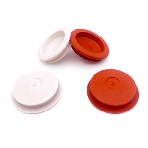 May include: Two white and two orange circular plastic plugs, each featuring a raised number 8 embossed in the center. These round components have a flat top surface and a wider base rim, designed for insertion into circular openings or holes.