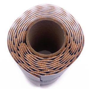 Puede incluir: Un rollo de baldosas de corcho, enrollado y asegurado con una etiqueta de papel blanco. Las baldosas de corcho son marrones y tienen una textura natural ligeramente rugosa. El rollo est&aacute; sobre un fondo blanco.