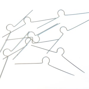 May include: A group of silver wire hangers, some are bent and overlapping, all are in a random arrangement on a white background.