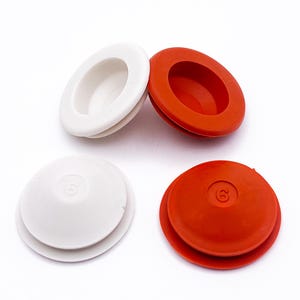 May include: Four rubber grommets in white and red. Two are oval-shaped, and two are circular with the number 6 embossed on the top. The grommets are designed to protect and seal holes in various applications.