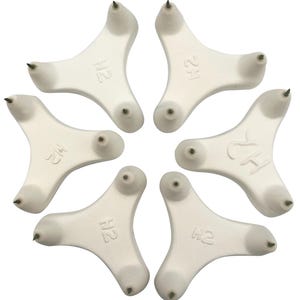 Könnte beinhalten: Sechs weiße, dreieckige Eisspikes aus Kunststoff mit jeweils drei Metallspitzen. Die Spikes haben den Text "H2" aufgedruckt.