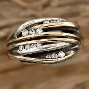 May include: A silver and gold ring with a woven design and small diamonds set in the metal.