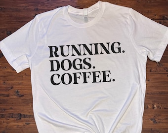 May include: White t-shirt with black text that reads "RUNNING. DOGS. COFFEE."