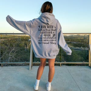 May include: Gray hooded sweatshirt with a motivational quote about running and faith: "Run with faith in your heart. Every step is a prayer. Every mile a testament and the finish line a glimpse of His Eternal Glory."