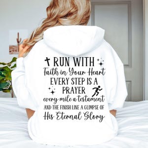 May include: White hooded sweatshirt with the text "RUN WITH Faith in Your Heart EVERY STEP IS A PRAYER every mile a testament AND THE FINISH LINE A GLIMPSE OF His Eternal Glory" printed on the back.