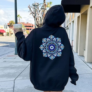 May include: Black hooded sweatshirt with a blue and white mandala design featuring an evil eye in the center.