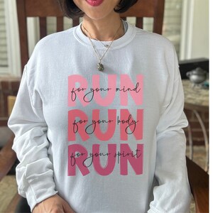 May include: White sweatshirt with a pink graphic that says "Run for your mind, Run for your body, Run for your spirit".