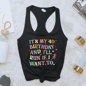 May include: Black racerback tank top with the text "IT'S MY 40TH BIRTHDAY AND I'LL RUN IF I WANT TO." in colorful letters. The design includes stars and a running figure.