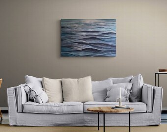 Puede incluir: Un sofá de lino gris claro con tres almohadas, una mesa de café de madera y una pintura de olas azules en la pared.