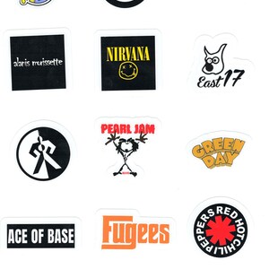 May include: A collection of stickers featuring band logos and names, including Nirvana, Pearl Jam, and Green Day. The stickers are various shapes and colors, with text and graphics. The background is white.