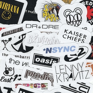 May include: A collection of white stickers with black text featuring band names like Nirvana, Backstreet Boys, and Oasis. Other stickers include the names Dr. Dre, Kaiser Chiefs, and Lenny Kravitz. The stickers are of various shapes and sizes.