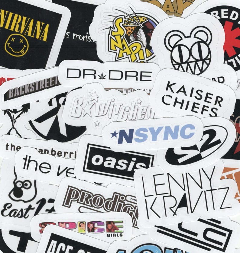 May include: A collection of white stickers with black text featuring band names like Nirvana, Backstreet Boys, and Oasis. Other stickers include the names Dr. Dre, Kaiser Chiefs, and Lenny Kravitz. The stickers are of various shapes and sizes.