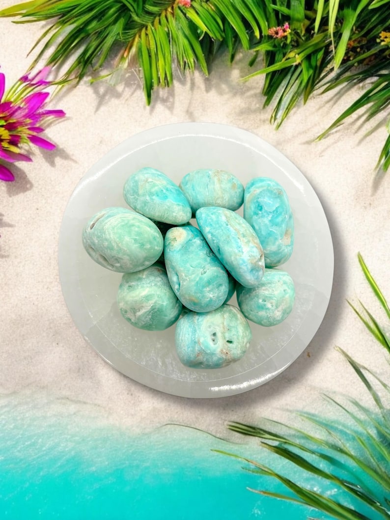 Pu&ograve; includere: Una ciotola bianca piena di pietre di agata rotolata di colore blu turchese e bianco. Le pietre sono lisce e levigate e hanno un aspetto naturale e organico.