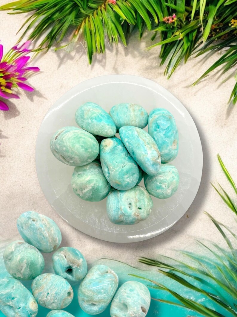 Pu&ograve; includere: Una ciotola bianca piena di pietre rotonde di colore blu chiaro e bianco. Le pietre sono lisce e hanno un motivo a spirale. La ciotola &egrave; appoggiata su una superficie bianca.