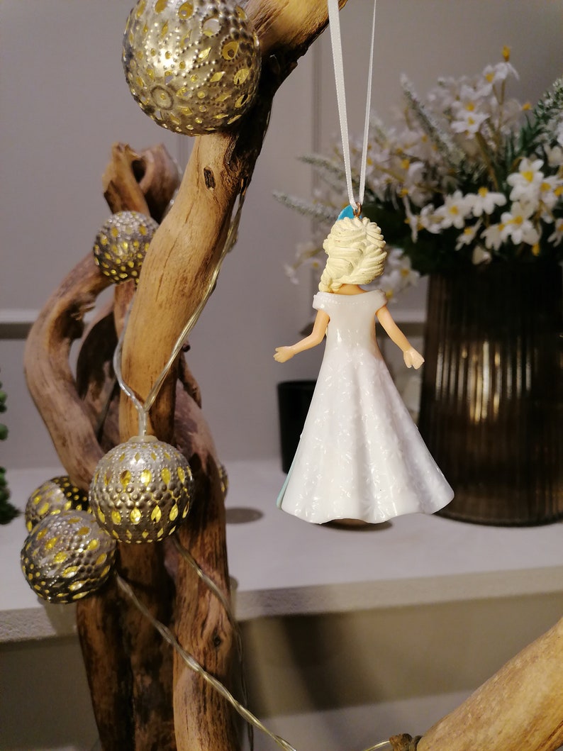 Peut inclure: Une figurine en porcelaine blanche repr&eacute;sentant une femme aux cheveux blonds portant une robe blanche. La figurine est suspendue &agrave; une ficelle blanche et est d&eacute;cor&eacute;e d'accents bleus.