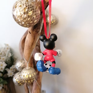 K&ouml;nnte beinhalten: Roter und blauer Weihnachtsbaumschmuck mit Mickey Mouse, der als Fu&szlig;ballspieler verkleidet ist und einen Fu&szlig;ball tritt.