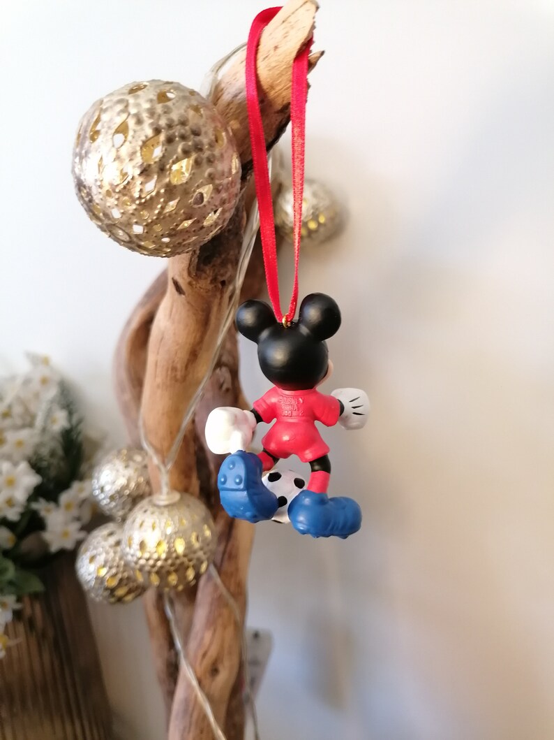 K&ouml;nnte beinhalten: Roter und blauer Weihnachtsbaumschmuck mit Mickey Mouse, der als Fu&szlig;ballspieler verkleidet ist und einen Fu&szlig;ball tritt.