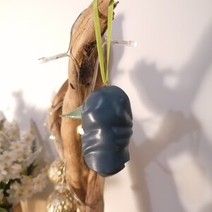 May include: A blue ceramic ornament shaped like a bird with a green ribbon hanging from it.