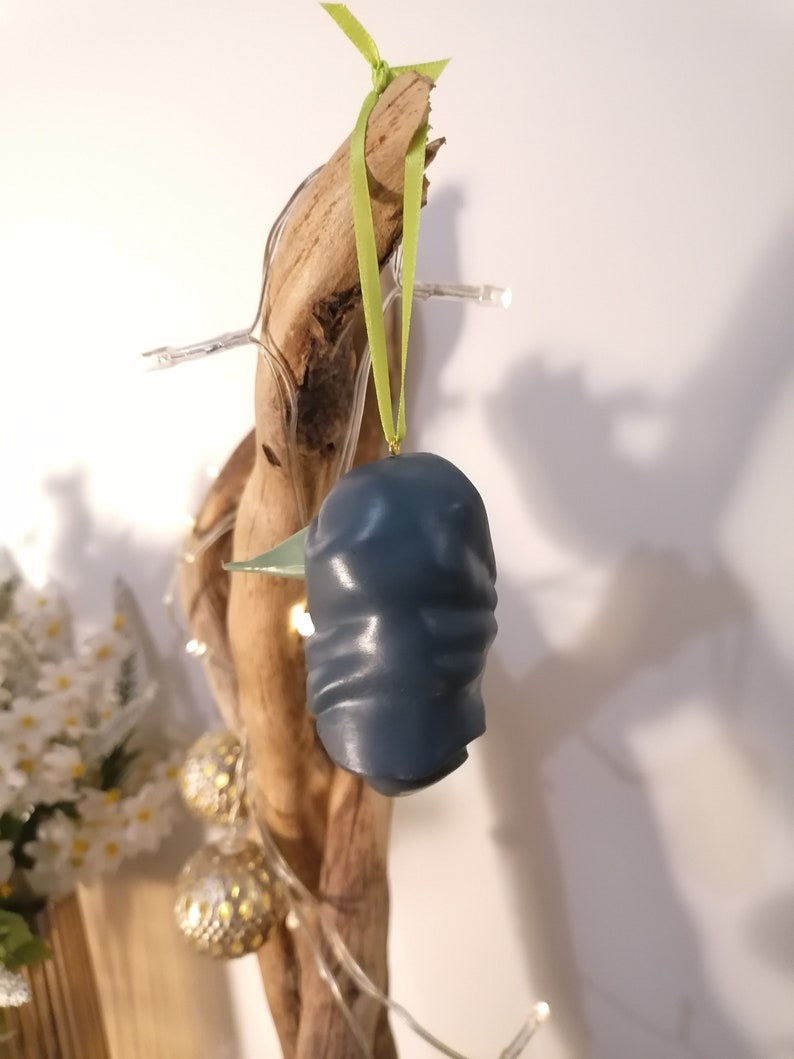 May include: A blue ceramic ornament shaped like a bird with a green ribbon hanging from it.