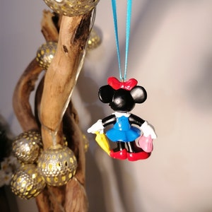 Op de afbeelding: Een blauwe en rode Minnie Mouse-versiering met een gele paraplu en een roze handtas die aan een blauw lint hangt.