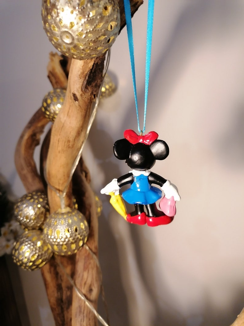 Op de afbeelding: Een blauwe en rode Minnie Mouse-versiering met een gele paraplu en een roze handtas die aan een blauw lint hangt.