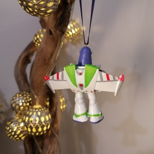 Pu&ograve; includere: Un ornamento a forma di ranger spaziale verde, bianco e rosso con testa blu e tuta spaziale verde e bianca. L'ornamento &egrave; appeso a un nastro blu.