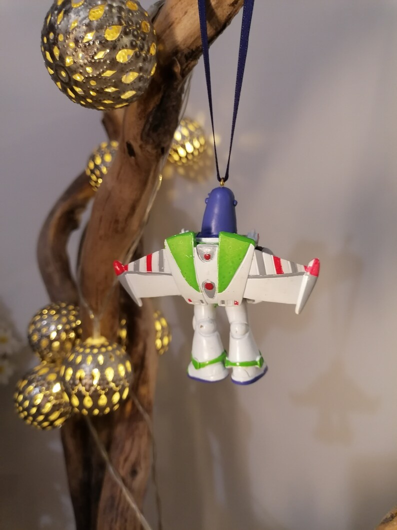 Pu&ograve; includere: Un ornamento a forma di ranger spaziale verde, bianco e rosso con testa blu e tuta spaziale verde e bianca. L'ornamento &egrave; appeso a un nastro blu.