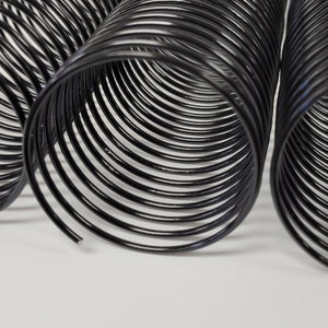 May include: Three black metal coil binding spines, each with a different length. The coils are made of a thin, flexible metal and are designed to bind documents together.