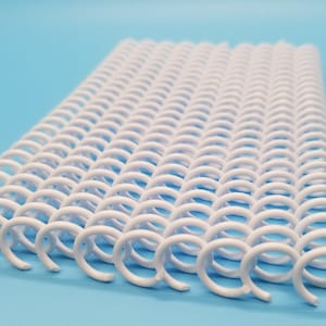 May include: White plastic coil binding for documents, papers, or books. The coils are arranged in a flat, rectangular shape.