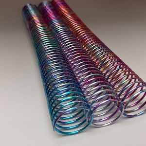 May include: Three iridescent metal coil binding spines in blue, green, purple, and pink.