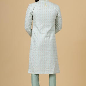 May include: A light blue kurta with a gold embroidered pattern. The kurta has long sleeves and a mandarin collar. The model is wearing matching light blue pants.