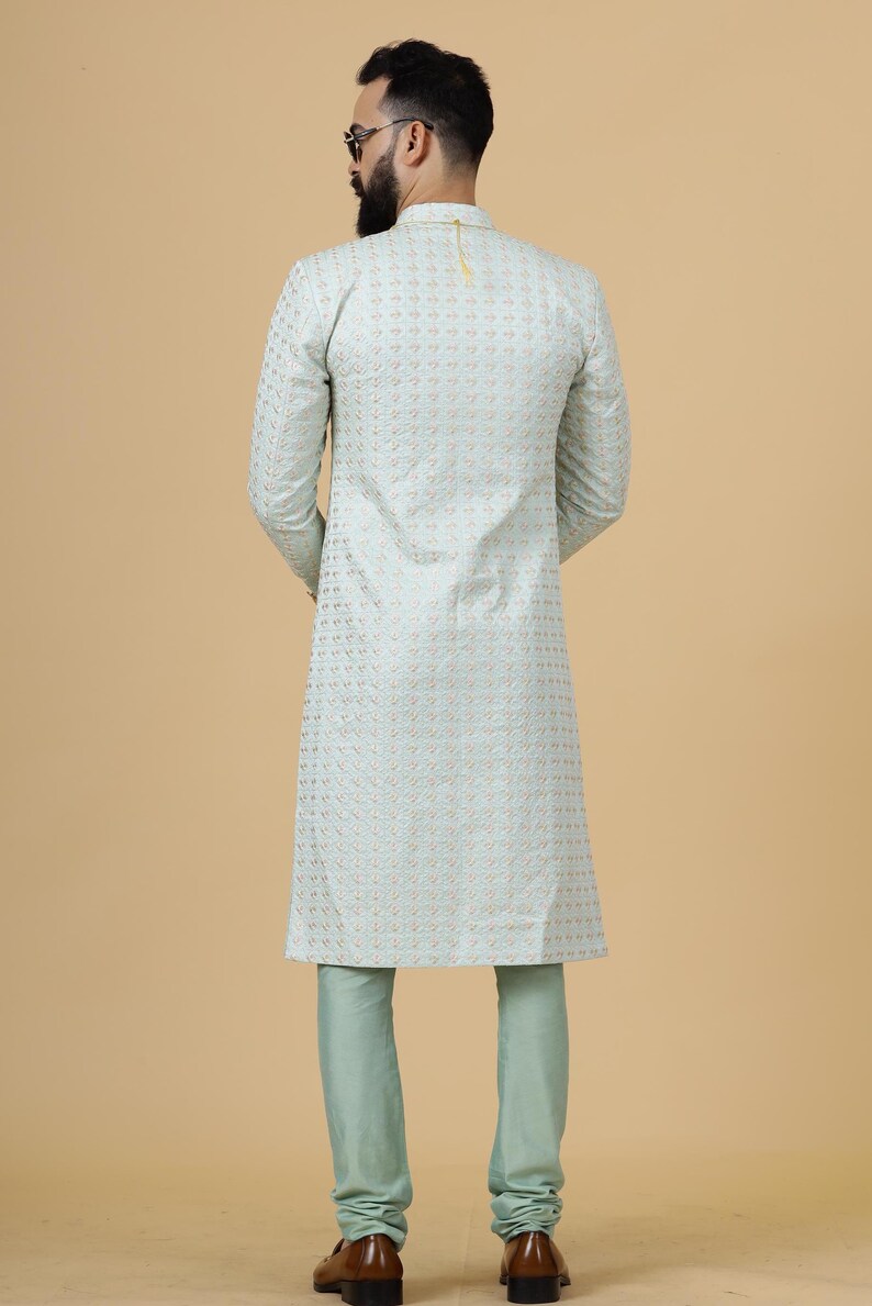 May include: A light blue kurta with a gold embroidered pattern. The kurta has long sleeves and a mandarin collar. The model is wearing matching light blue pants.