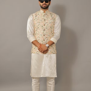 Puede incluir: Un hombre con una kurta blanca y pantalones a juego con un chaleco estampado floral. Lleva gafas de sol y un reloj.