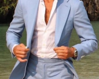 May include: A light blue linen suit with a white button-down shirt. The suit jacket is unbuttoned and the shirt is open at the collar.