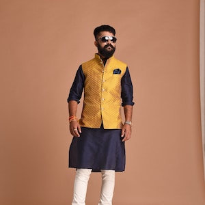 May include: A man wearing a navy blue kurta with a gold brocade waistcoat, white pants, and sunglasses.