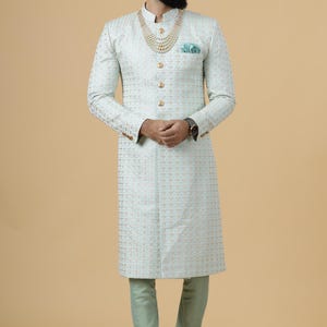 May include: A light blue patterned long-sleeved kurta with gold buttons and a gold necklace. The kurta is worn with matching light blue pants and brown shoes.