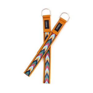 May include: Two mustard yellow straps with a colorful chevron pattern and silver metal loops. The straps have the word "RAINBO" printed on them.