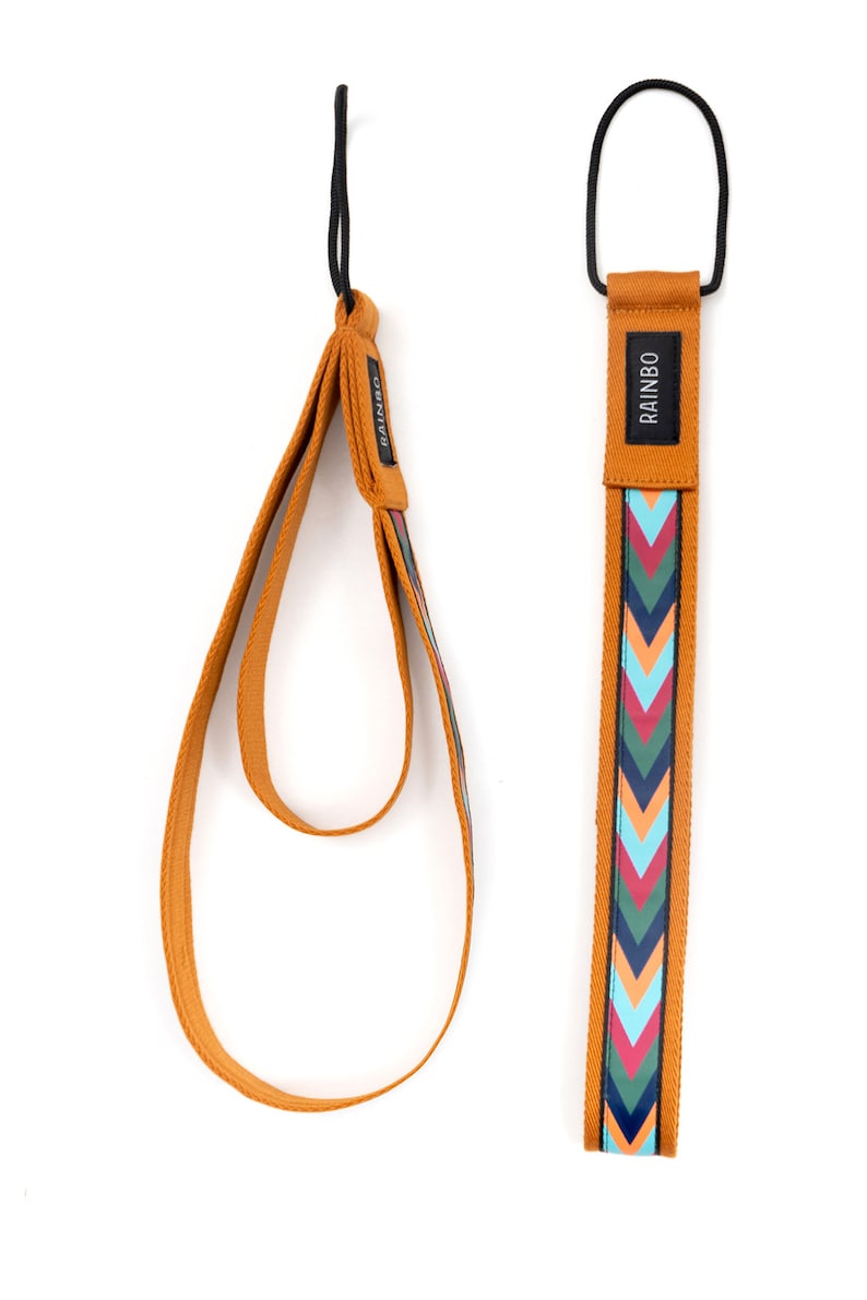 May include: Two brown straps with a chevron pattern in shades of blue, green, pink, and orange. The strap on the right has the word "RAINBO" printed on it.