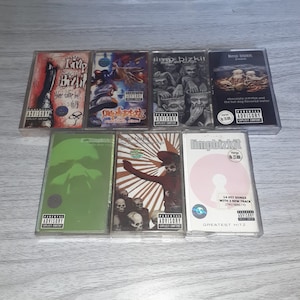 Puede incluir: Colección de siete cintas de casete con portadas de álbumes de la banda Limp Bizkit. Las cintas muestran varios diseños y el logotipo de Parental Advisory. Los títulos incluyen "Chocolate Starfish and the Hot Dog Flavored Water" y "Greatest Hitz."
