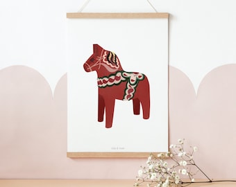 May include: A red and white Dala horse illustration with green and brown details. The illustration is framed and hanging on a white wall with a pink scalloped border.