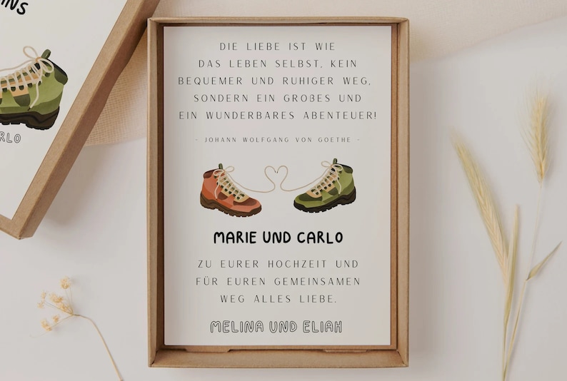 May include: A white card with a quote about love being an adventure, illustrated with two hiking boots connected by a heart. The card reads "Die Liebe ist wie das Leben selbst. Kein bequemer und ruhiger Weg, sondern ein gro&szlig;es und ein wunderbares Abenteuer! - Johann Wolfgang von Goethe - Marie und Carlo Zu eurer Hochzeit und f&uuml;r euren gemeinsamen Weg alles Liebe. Melina und Elijah"